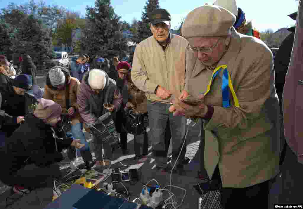 Liberated residents take advantage of a charging station in the central square. &nbsp;