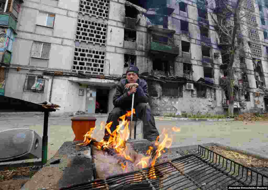 Many residents in the Russian-controlled city of Mariupol are also dealing with no electricity, water, or gas supplies, such as this man warming himself by a fire on November 16.