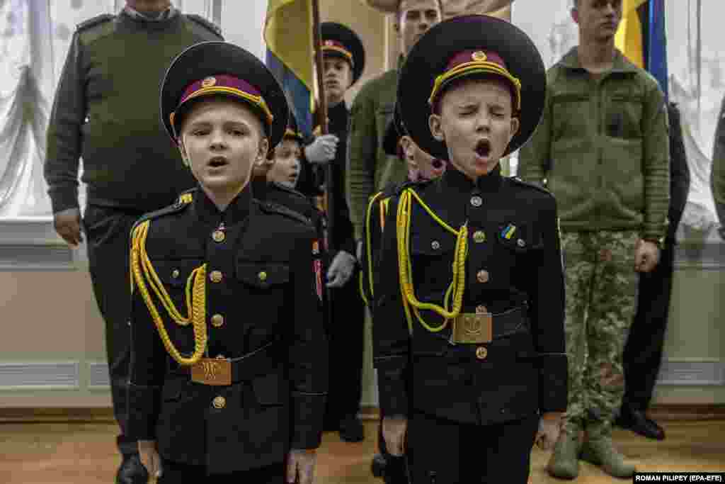 Disa vogëlushë ukrainas të veshur si ushtarakë shihen duke kënduar gjatë një ceremonie në Liceun e Shtetit në Kiev.&nbsp;