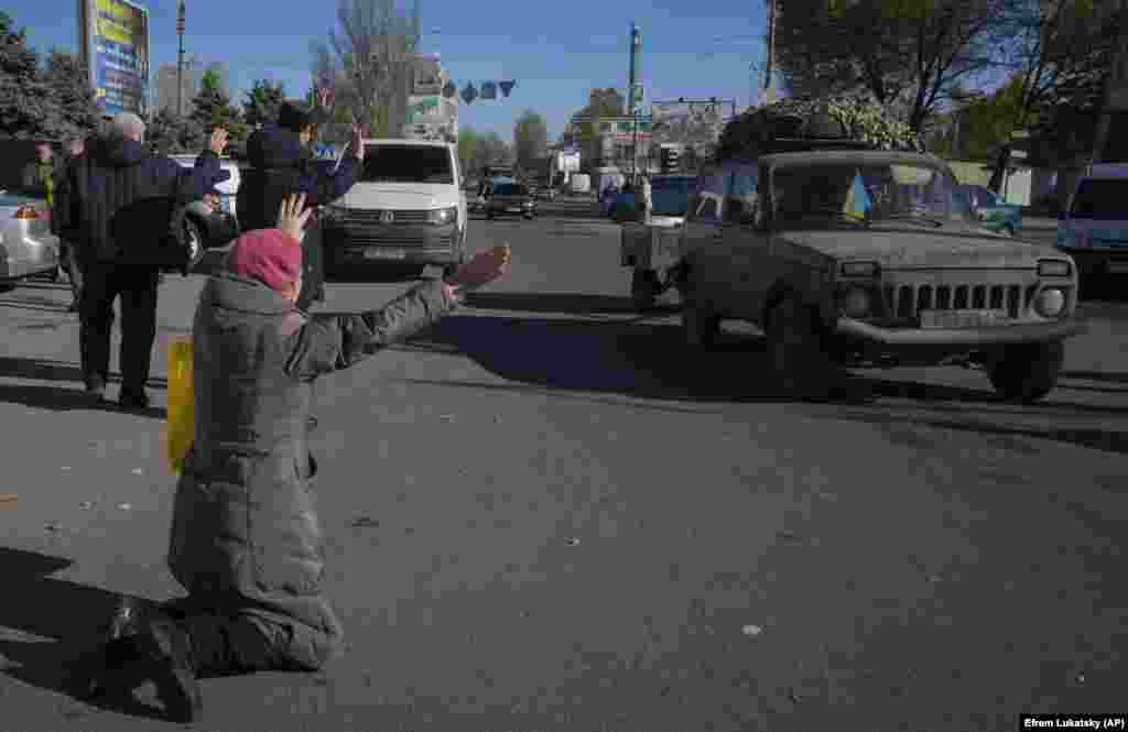 The atmosphere in the 18th-century port city continues to be euphoric. Here, residents wave and kneel to passing Ukrainian Army personnel on November 15.