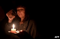 Iren Rozdobudko, scriitor și lector la universitates, în vârstă de 60 de ani, bând un pahar cu apă la lumina lumânărilor în timpul unei întreruperi de curent în locuința sa din nordul capitalei ucrainene Kiev. Din 10 octombrie, sistemul electric ucrainean a fost puternic afectat de multiple atacuri rusești care au vizat infrastructura energetică.