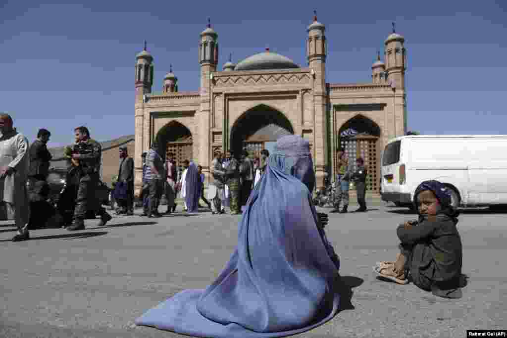 An Afghan woman waits for alms during the first day of Eid al-Fitr in Kabul, Afghanistan.