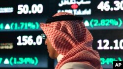 A Saudi man walks at the Tadawul Saudi Stock Exchange, in Riyadh, Saudi Arabia, Monday, June 15, 2015. Saudi Arabia's stock market, valued at $585 billion, opened up to direct foreign investment for the first time Monday, as the kingdom seeks an economic 