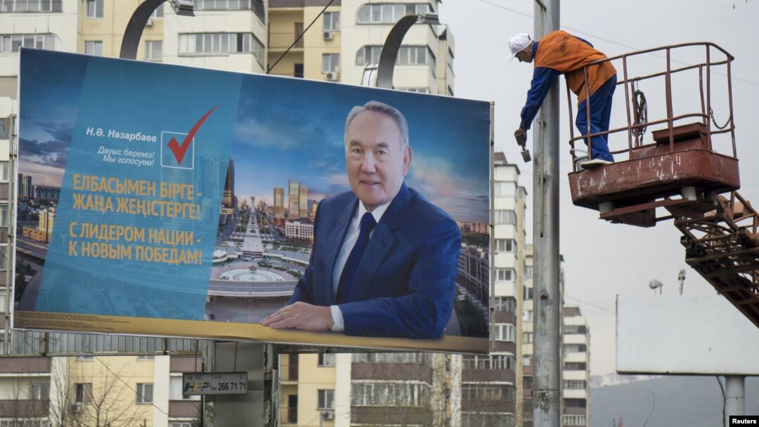 Жұмысшы Қазақстан президенті Нұрсұлтан Назарбаевтың сайлау жарнамасы ілінген билборд жанындағы бағанды бояп жатыр. Алматы, 14 сәуір 2015 жыл.