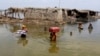 Women carry belongings salvaged from their flooded home after monsoon rains in Sindh Province on September 6.