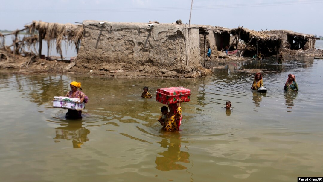 Women carry belongings salvaged from their flooded home after monsoon rains in Sindh Province on September 6.