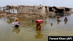 Women carry belongings salvaged from their flooded home after monsoon rains in Sindh Province on September 6.