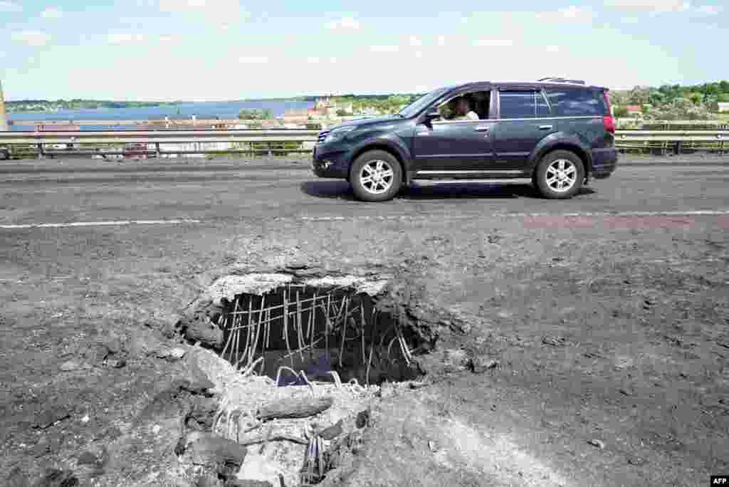 A car passes rocket damage on the Antonivskiy Bridge. A few days after this picture was taken on July 21, the crossing was hit by further Ukrainian strikes, and Russian-imposed authorities closed the crossing.