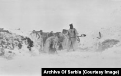 Ushtarë të paidentifikuar duke pastruar borën nga një pozicion gjatë një stuhie dimri.