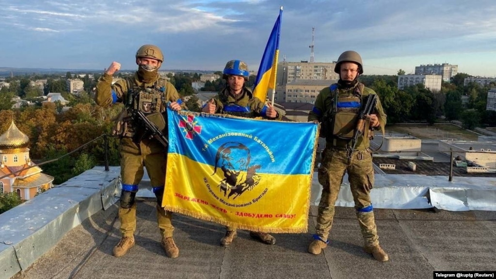 Ukrainian soldiers hold a flag on a rooftop in Kupyansk on September 10. Kupyansk is a transportation hub in eastern Ukraine and strategically important for supplying Russian troops in the Donbas region.