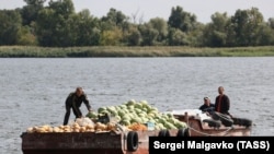 Люди перевозят фрукты и овощи на другой берег Днепра Херсонщины на лодках, поскольку все мосты в городе повреждены