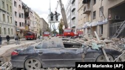 Украинските пожарникари работат меѓу оштетените згради по руски ракетен напад во центарот на Харкив, 6 септември 2022 година