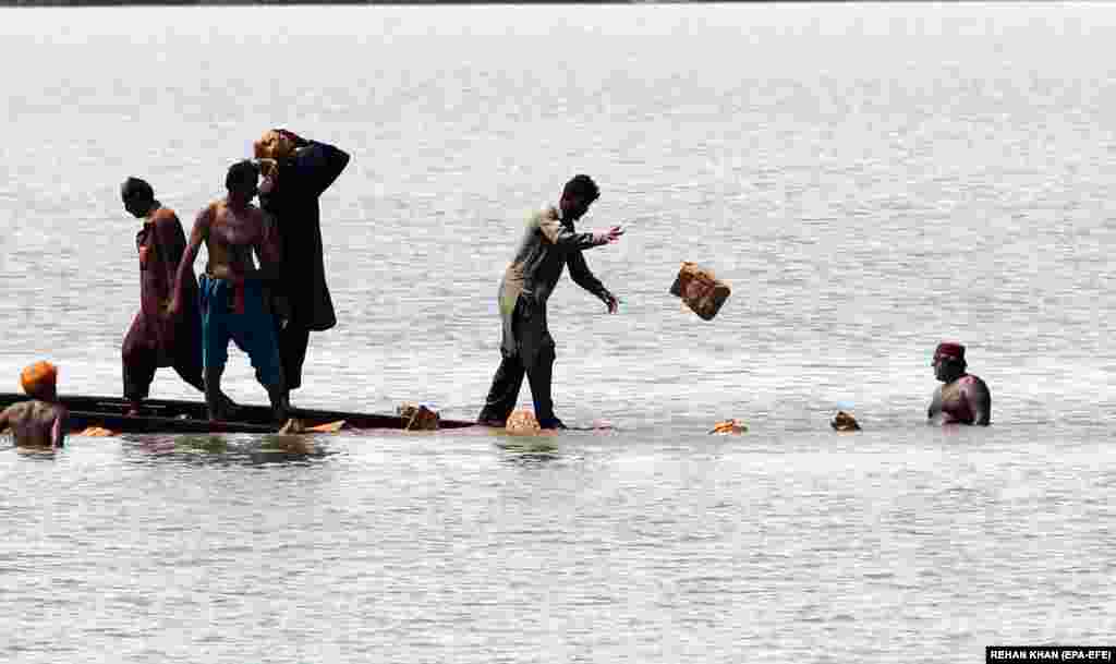 Punonjësit pakistanezë të hekurudhave duke riparuar binarët në një zonë të përmbytur të provincës Sindh.