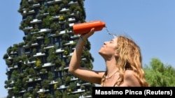 Një grua flladitet me ujë të ftohtë për ta luftuar motin e nxehtë. Millano, Itali.
