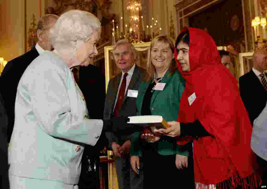 Yousafzai gives a copy of her book to Queen Elizabeth II during a reception at Buckingham Palace in London on October 18, 2013.
