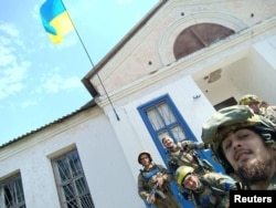 Солдаты фотографируются на фоне украинского флага в освобожденном селе Василенково Харьковской области, 10 сентября 2022 года