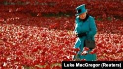 Regina Elisabeta străbate un lan de maci din ceramică, parte a instalației artistice „Sângele a șters pământuri și mări de roșu” de la Turnul Londrei, pentru comemorarea a 100 de ani de la începerea Primului Război Mondial, Londra, 16 octombrie 2014.