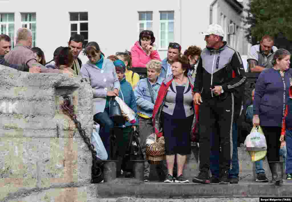 Passengers wait in line at a port used to ferry people across the Dnieper River on September 8. After repeated attempts to repair the Antonivskiy Bridge, and establish a pontoon crossing, a member of the Russian-imposed local government of Kherson said on September 6 that those efforts were being suspended &quot;because there is no point, there is no expediency.&quot; &nbsp;