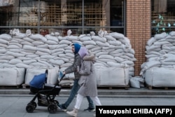 A couple walk by a shop covered by sandbags in Dnipro.