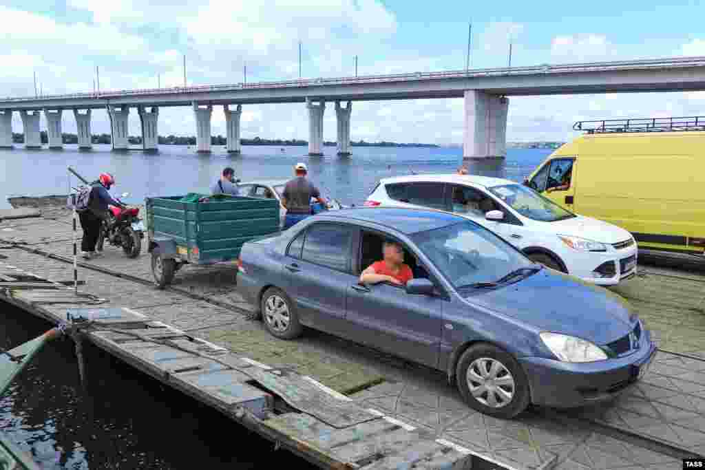 A pontoon ferry transports cars alongside the Antonivskiy Bridge on August 3, shortly after the bridge was closed. It is believed that U.S.-supplied high-mobility artillery rocket systems (HIMARS) were used in the strikes on the bridge. Ukrainian forces are currently close enough to Kherson to be well within the 92-kilometer range of the weapons system.&nbsp;