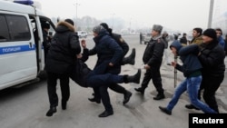 Задержанных на площади Республики участников акции протеста против одномоментной девальвации силой ведут в полицейскую машину. Алматы, 15 февраля 2014 года.