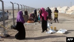 Displaced Iraqis from the embattled city of Fallujah carry bags of food provided by the World Food Program at a camp where they are taking shelter on June 10 some 30 kilometers south of the city.