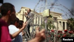 Egypt - A protester standing on a barricade, shouts in front of soldiers outside the Supreme Constitutional Court in Cairo, 14Jun2012