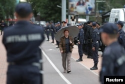 Женщина на фоне полицейского усиления в Алматы 12 июня в районе предполагаемого митинга.