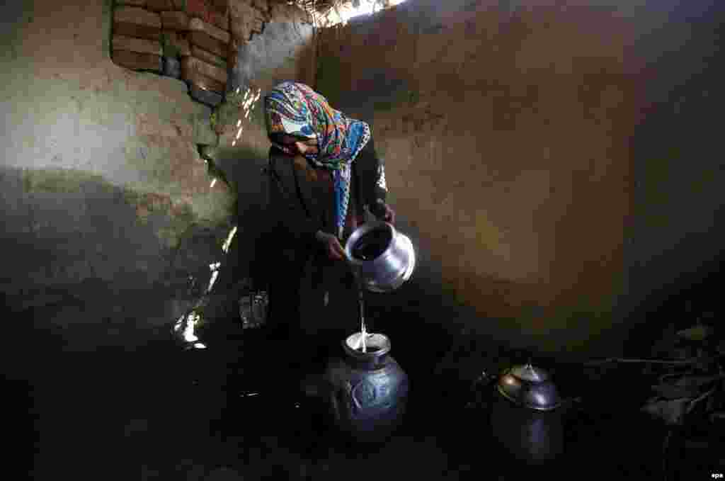 A Kashmiri woman fills a pot with water after collecting it from a river in Pattan, north of Srinagar, the summer capital of Indian Kashmir. (epa/Farooq Khan)