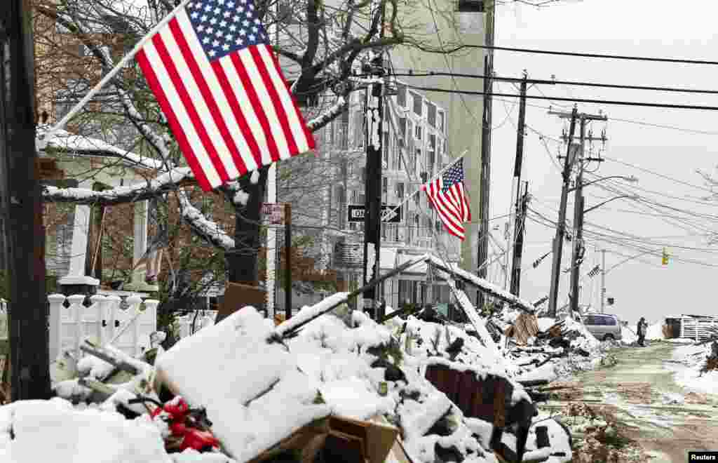 A man stands in a street in New York among piles of debris outside homes due to flooding from superstorm Sandy. The debris is now covered in snow left by a subsequent storm. (Reuters/Lucas Jackson)