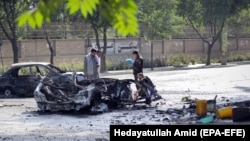 Afghan security officials inspect the scene of a bomb blast outside Kabul University on July 19.