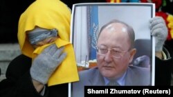 A woman holds a portrait of Altynbek Sarsenbaiuly at the funeral of the prominent opposition politician in Almaty in 2006.