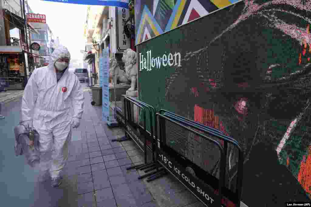 Un angajat al biroului districtual al sănătății îmbrăcat în echipament de protecție dezinfectează o stradă din Seul, ca măsură de precauție împotriva coronavirusului, Coreea de Sud, 29 octombrie 2021.