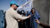 A UNHCR worker explains aid collection procedures to displaced Afghan women on the outskirts of Kabul. (file photo)