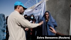 A UNHCR worker explains aid collection procedures to displaced Afghan women on the outskirts of Kabul. (file photo)