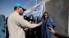 A UNHCR worker explains aid collection procedures to displaced Afghan women outside a distribution center on the outskirts of Kabul on October 28.