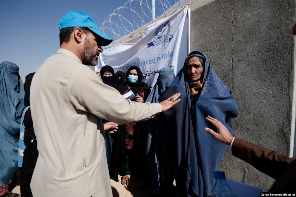 A UNHCR worker explains aid collection procedures to displaced Afghan women on the outskirts of Kabul. (file photo)