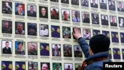 A woman touches a portrait of her husband in Kyiv, on a banner with portraits of Ukrainian servicemen killed in the conflict with pro-Russian separatists in eastern Ukraine.