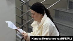 Айсулуу Кудайбердиева Равшан Жээнбеков берген катты окуп жатат.