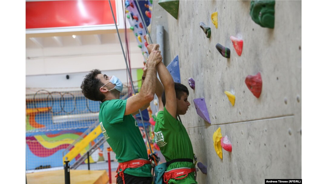 Răzvan Nedu, căpitanul Lotului Național de Paraclimbing, îi indică mișcările pe traseu sportivului nevăzător Angelo Simionescu, în timpul antrenamentului de la Centrul Climb Again din București.