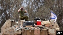 Un soldat israelian folosește un binoclu în timp ce stă pe un tanc într-o zonă din apropierea graniței de sud a Israelului cu Fâșia Gaza, pe 28 mai 2024.