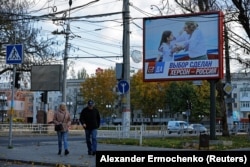 Люди идут по улице рядом с транспарантом с надписью «Выбор сделан. Херсон — это Россия» накануне освобождение города украинскими войсками, 31 октября 2022 года