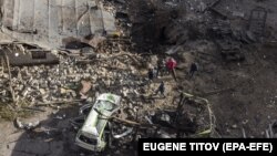 People stand near a hole after recent Russian shelling at a factory in Kharkiv on November 3.