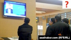 Aşgabadyň aeroportunda telewizora tomaşa edýän ýaşaýjylar.