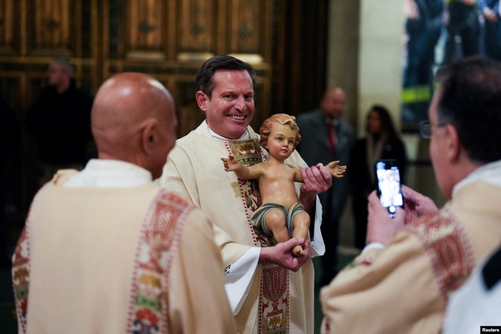 Një anëtar i klerit mban një statujë të foshnjës së Krishtit në meshën e mesnatës në Katedralen e Shën Patrikut në qytetin e Nju Jorkut.