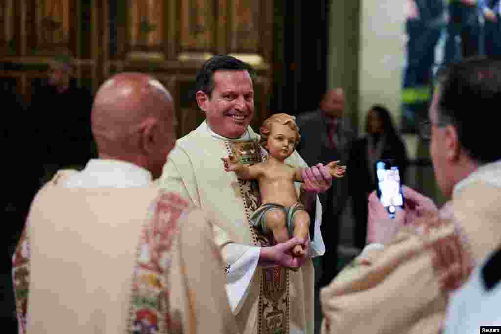 Një anëtar i klerit mban një statujë të foshnjës së Krishtit në meshën e mesnatës në Katedralen e Shën Patrikut në qytetin e Nju Jorkut.