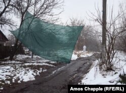 Mesh strung up across a village road to prevent sniper fire.