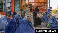 آرشیف- زنان فقیر در نزدیک یک خبازی در کابل نشسته اند تا اگر برخی افراد چند قرص نان خشک را بطور رایگان به آنها کمک کند