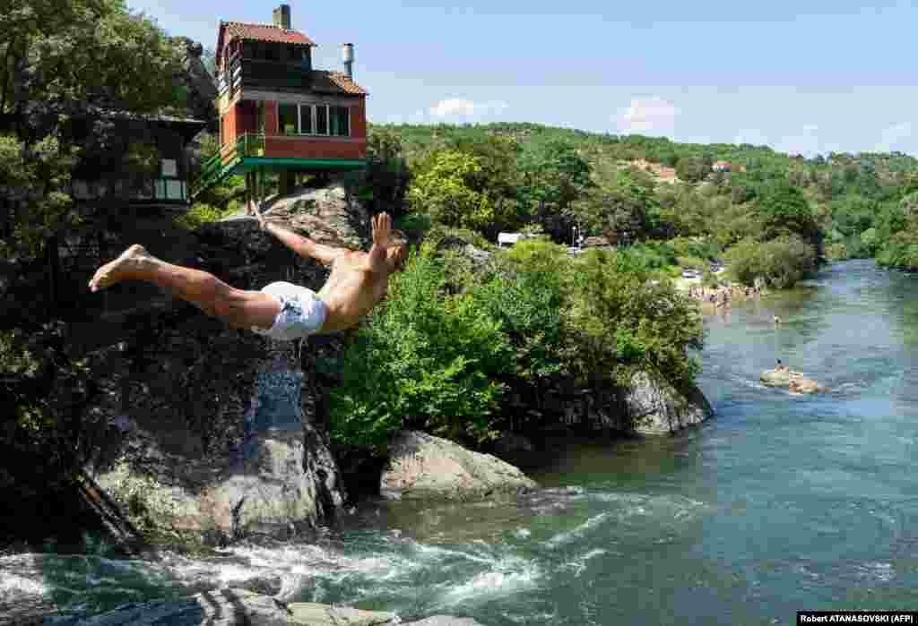 Молодой человек ныряет в реку Треска недалеко от Скопье во время жары в Македонии