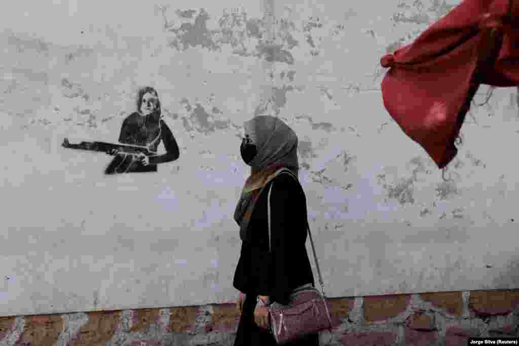 Egy nő sétál el egy kabuli épület falára felfestett graffiti előtt október 3-án